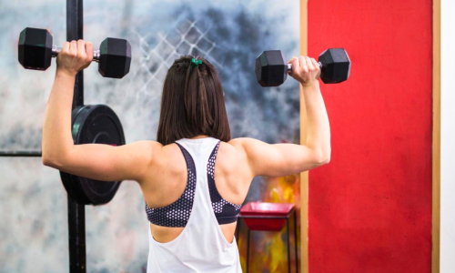 Woman strength training with dumbbells during a GLP-1 weight loss journey.